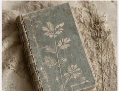 A muted botanical fabric journal on layered vintage textiles