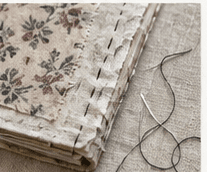 Hand stitching along a floral fabric journal cover